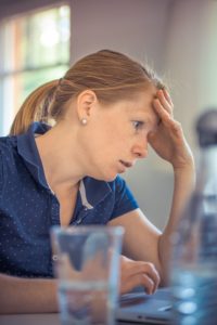 woman with hand on forehead while working