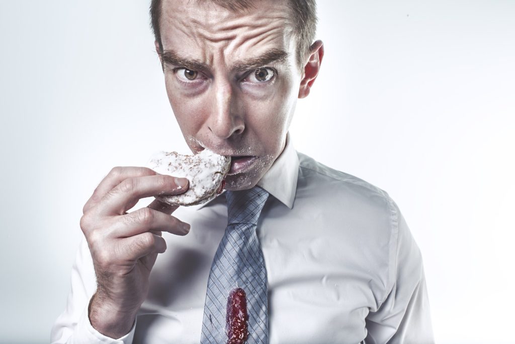 frowning man eating jelly donut